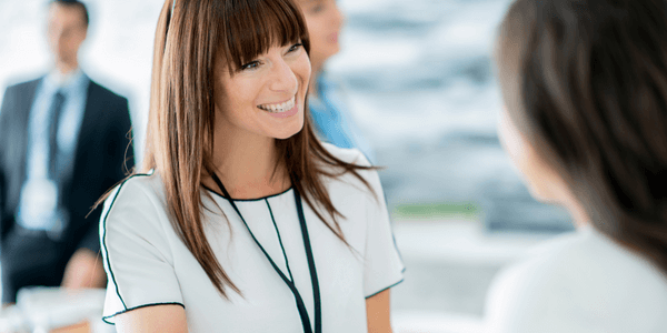 woman smiling talking to another women at a business networking event