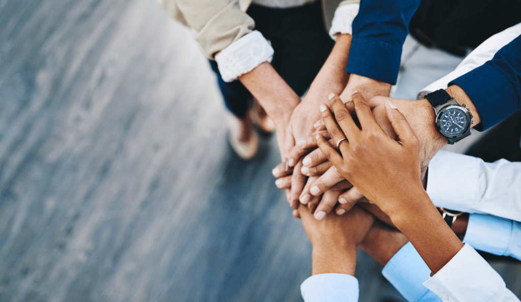 Image shows business men and women's hands on top of one another